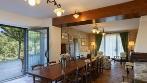 A spacious dining area with a long wooden table and chairs, a stone wall, and a view of the outdoors. - La Badia by Interhome (Vicchio)