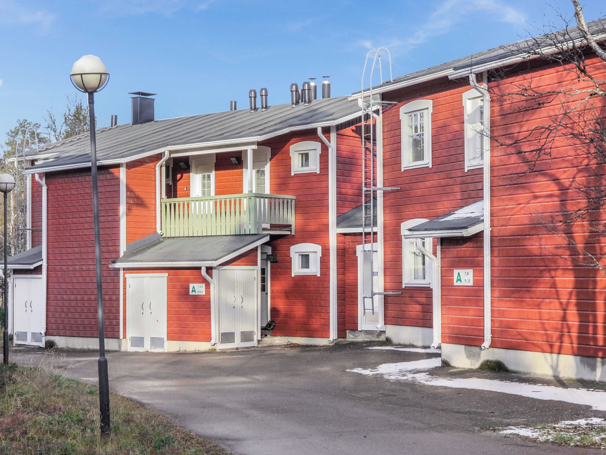 Een rood gebouw met een balkon, een garage en een klein portaaltje.