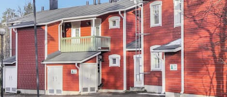 Ein rotes Gebäude mit Balkon, Garage und kleiner Veranda.