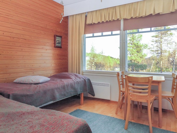 A room with two beds, a table, and chairs.