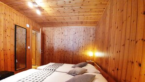 Una habitación con paneles de madera, una cama, un espejo y una mesita de noche con una lámpara.