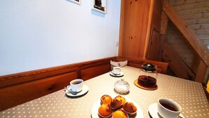 Una mesa de comedor con mantel de lunares, una tetera, una taza de té, un plato de muffins y una taza de café.