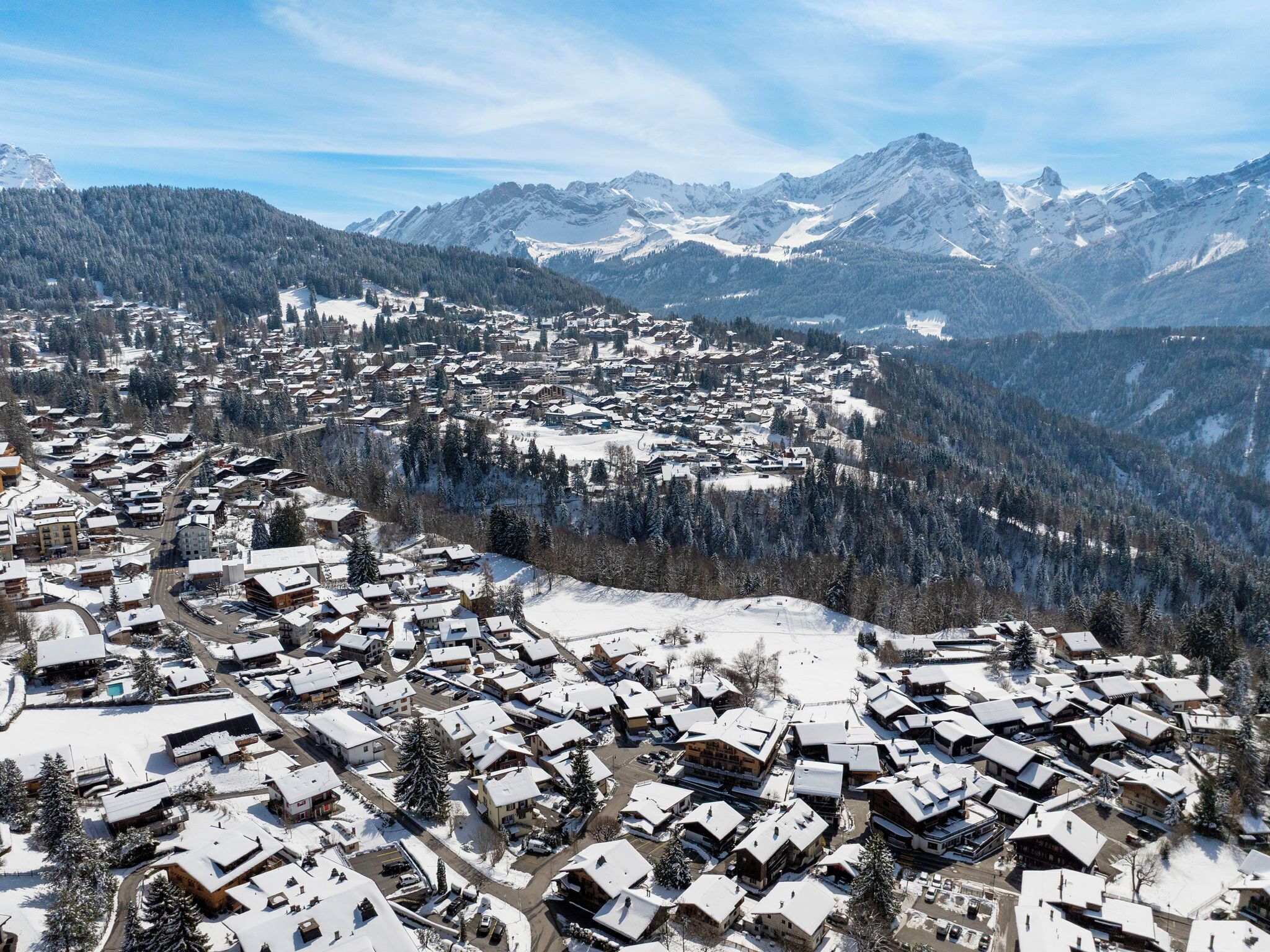 A snow-covered town with buildings and mountains in the background.