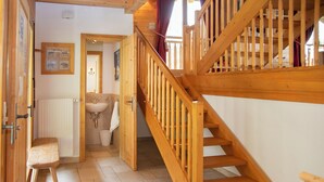 A wooden staircase leading to an upper floor, a sink, and a bench in a hallway. - Khamariah by Interhome (Villars)