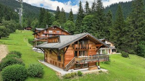 A wooden chalet with a balcony, surrounded by lush greenery and mountains. - Khamariah by Interhome (Villars)