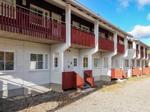 A multi-story building with balconies, a gravel driveway, and a clear sky.