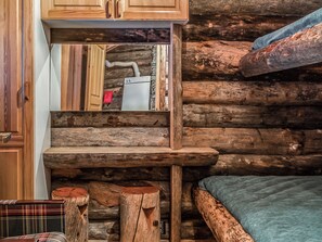 Ein rustikales Blockhaus-Interieur mit Etagenbett, Holzwänden und einer kleinen Küchenzeile.