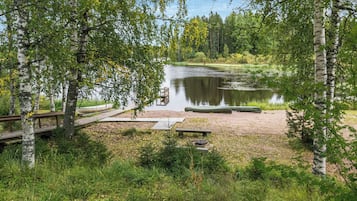 A serene lakeside campsite with a dock, picnic tables, and a boat.