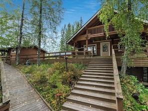 Une cabane en bois avec un escalier en bois menant à une véranda.