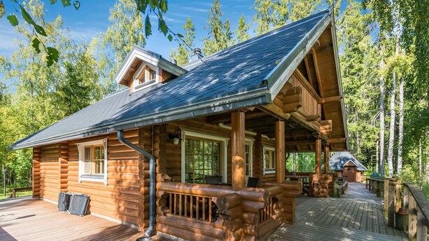 A log cabin with a covered porch, a dining area, and a small cabin-like structure. - Koivuranta by Interhome (Jämijärvi)