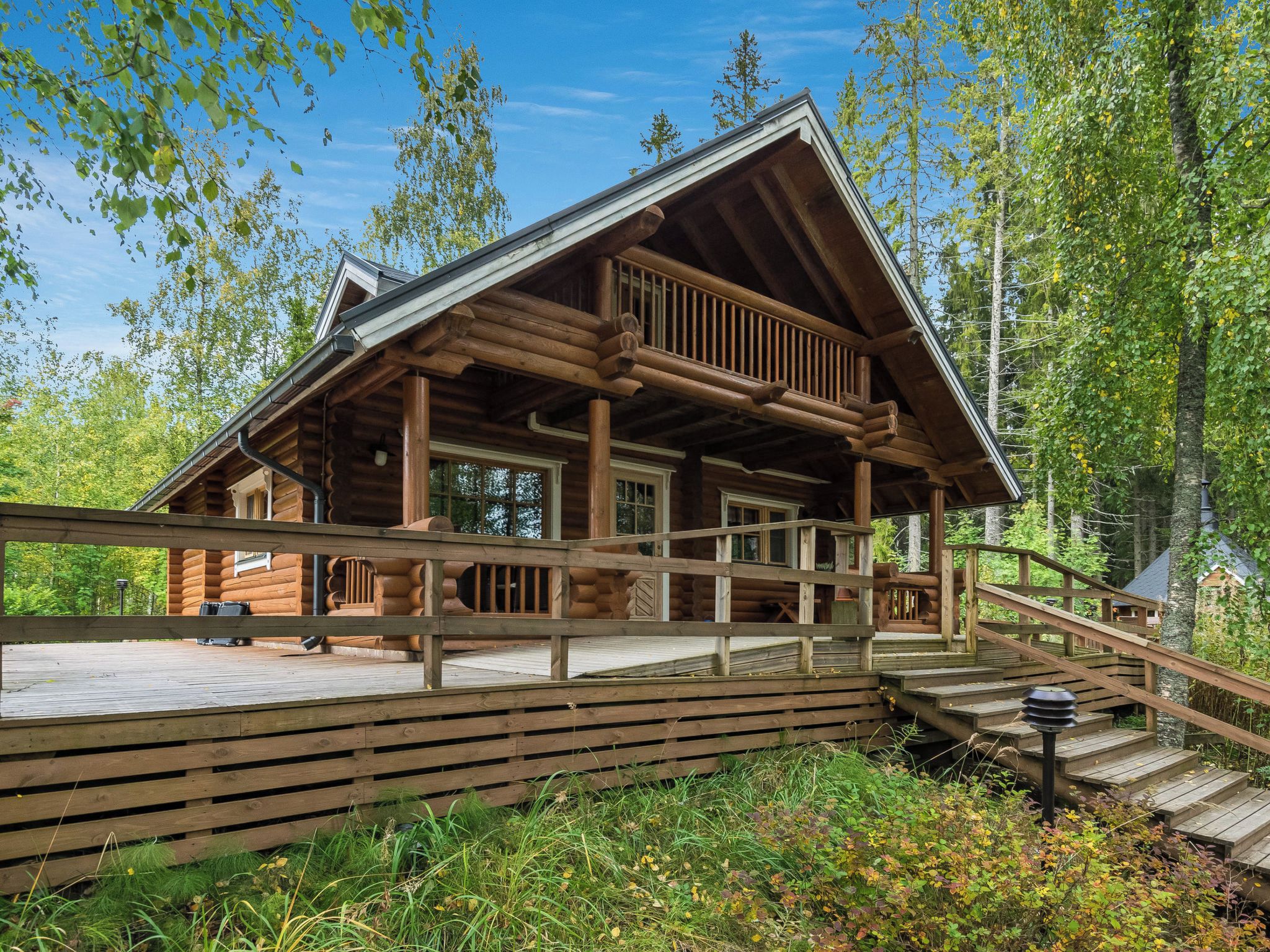 A log cabin with a wooden deck and a staircase leading to the entrance.