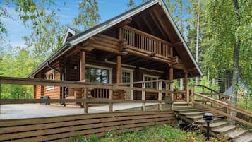 A log cabin with a wooden deck and a staircase leading to the entrance.