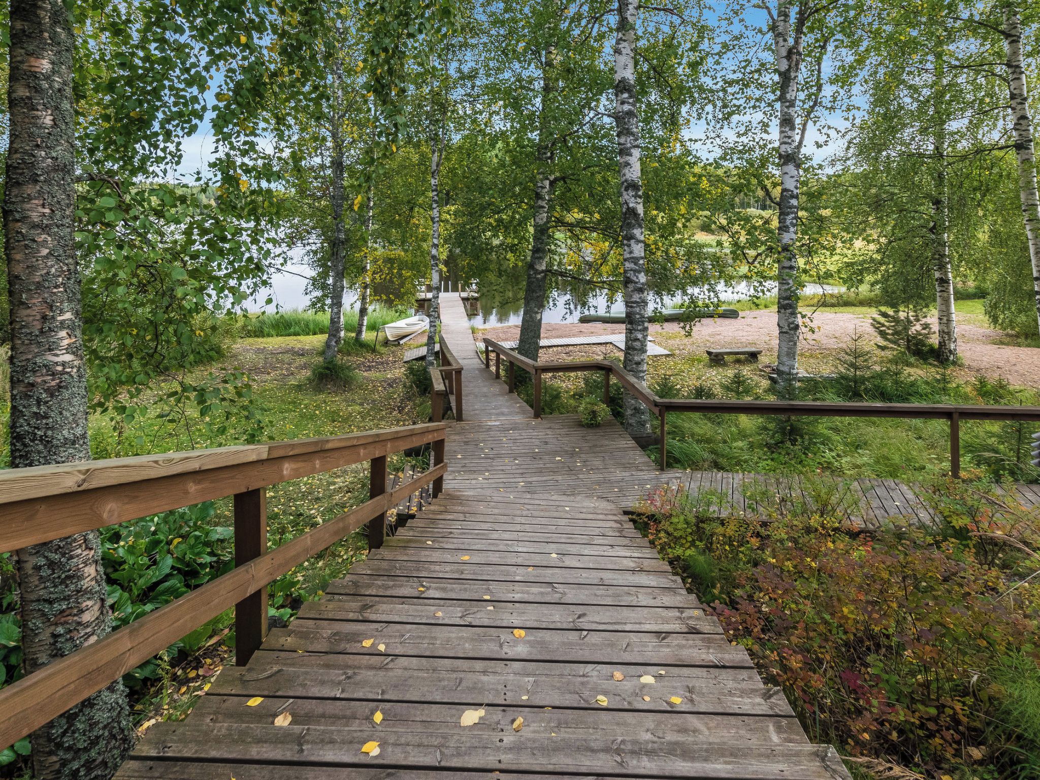 A wooden boardwalk leading to a dock by a lake, surrounded by trees.