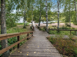 A wooden boardwalk leading to a dock by a lake, surrounded by trees. - Koivuranta by Interhome (Jämijärvi)