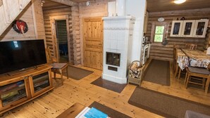 A log cabin interior with a fireplace, wooden floors, a television, and a dining area. - Koivuranta by Interhome (Jämijärvi)