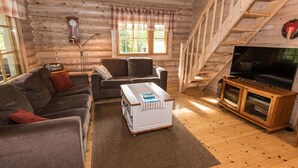 A cozy log cabin interior with a sofa, armchairs, a coffee table, a TV, and a bookshelf. - Koivuranta by Interhome (Jämijärvi)
