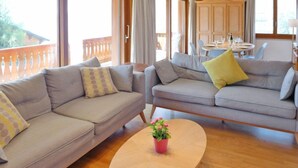 A modern living room with two grey sofas, a wooden coffee table, and a balcony with a wooden railing. - Hyacinthe 11 by Interhome (Villars)