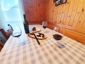 A table with a checkered tablecloth, a bottle of wine, a glass of wine, a plate with a piece of cake, and a knife. - Bergdohle by Interhome (Randa)