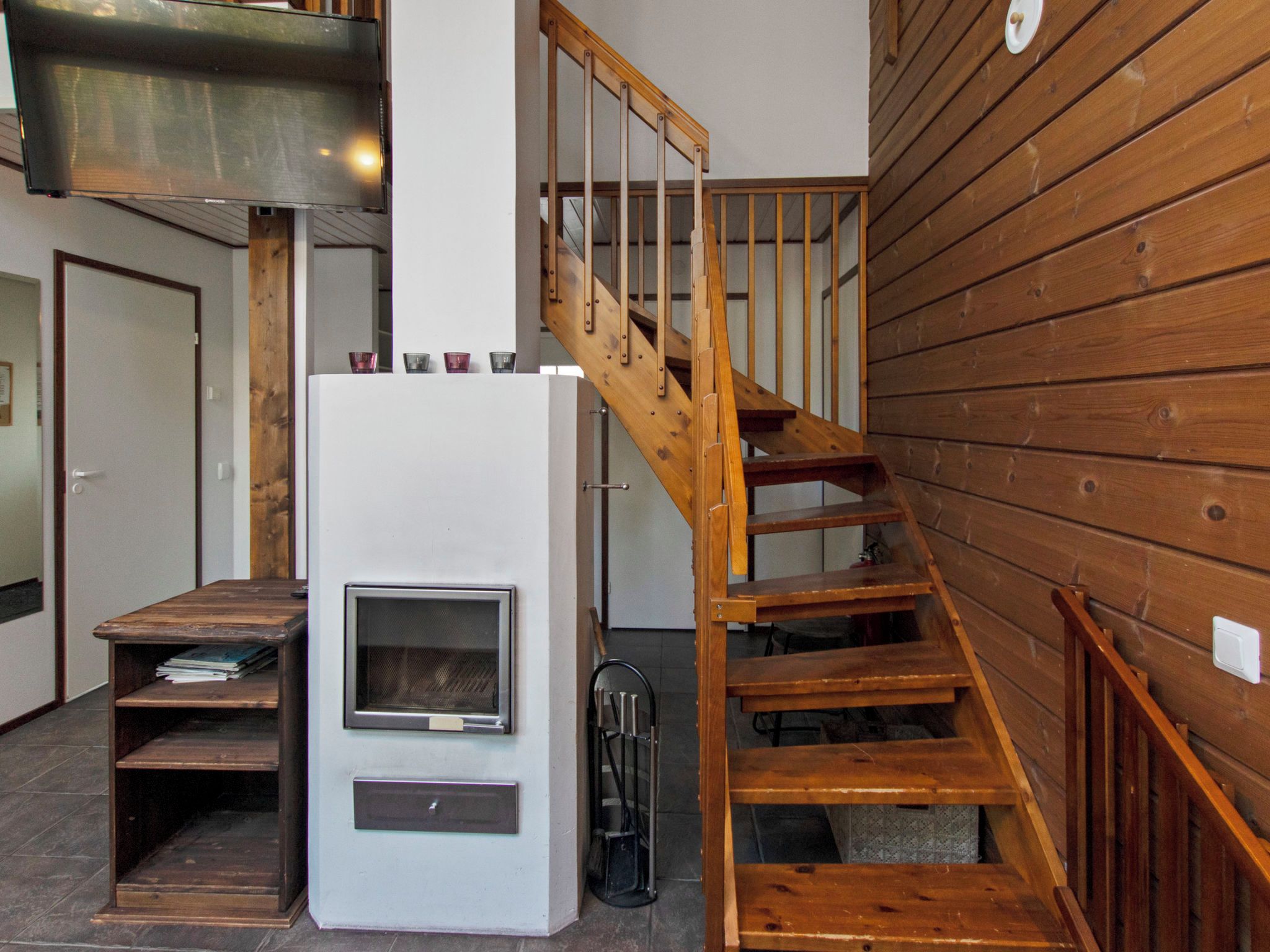 A modern interior with a wooden staircase, a white wall-mounted heater, and a wooden shelf.