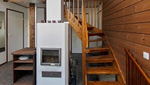 A modern interior with a wood-paneled wall, a white fireplace, and a wooden staircase.