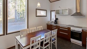 A compact kitchen with a dining table, chairs, a stove, and a microwave.