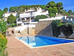 Un área de piscina con un muro de piedra y un edificio con varios balcones.