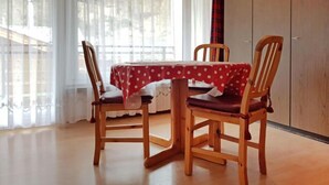 Un comedor con una mesa cubierta por un mantel de lunares, sillas de madera y vistas amplias a través de grandes ventanales.