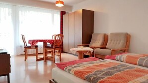 Una habitación de hotel con cama, dos sillas, una mesa y un armario.