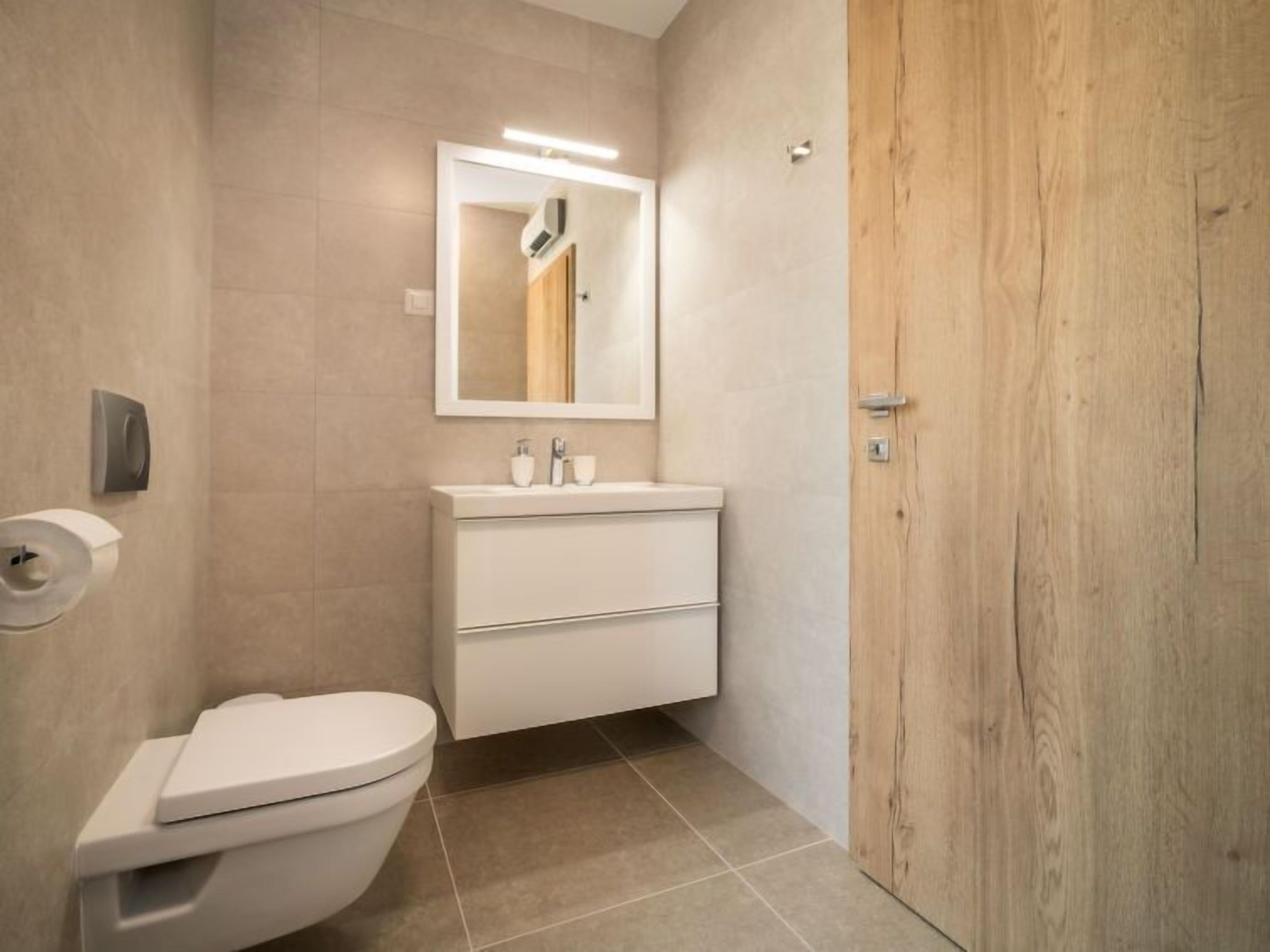 Een moderne badkamer met toilet, wastafel en spiegel.