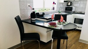 Eine moderne Küche mit schwarzem Arbeitsplatz, weißen Schränken und Holzboden. Es gibt eine Kaffeemaschine, eine Mikrowelle und ein Spülbecken.
