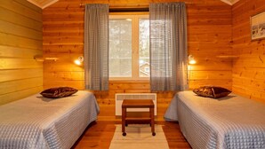 A cabin room with two beds, a small table, and a window with curtains.