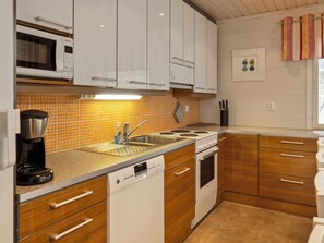 A compact kitchen with white cabinets, a stainless steel sink, a coffee maker, and a Siemens dishwasher. - Jutapirtti by Interhome (Kittilä)