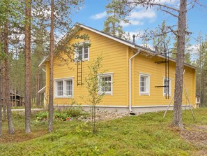 A yellow house with a gabled roof surrounded by trees and a grassy area. - Jutapirtti by Interhome (Kittilä)