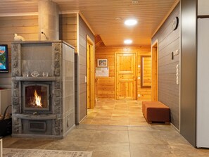 A hallway with a stone fireplace, wooden doors, and a bench. - Jutapirtti by Interhome (Kittilä)