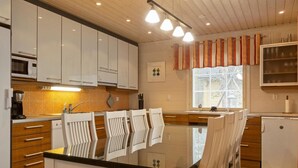 A modern kitchen with white cabinets, a black countertop, and a dining area with white chairs.