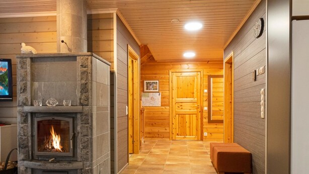 A cozy interior with a stone fireplace, wooden walls, and a tiled floor.