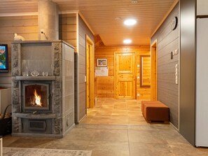 Een knus interieur met een stenen openhaard, houten wanden en een betegelde vloer.