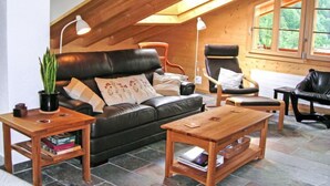 Ein gemütliches Loftsesselzimmer mit Holzbalkendecke, Ledersofa und zwei Sesseln.