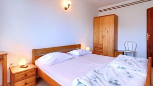 Ein Schlafzimmer mit einem hölzernen Bett, einem Nachttisch mit Lampe, einem Kleiderschrank und einem Sessel.