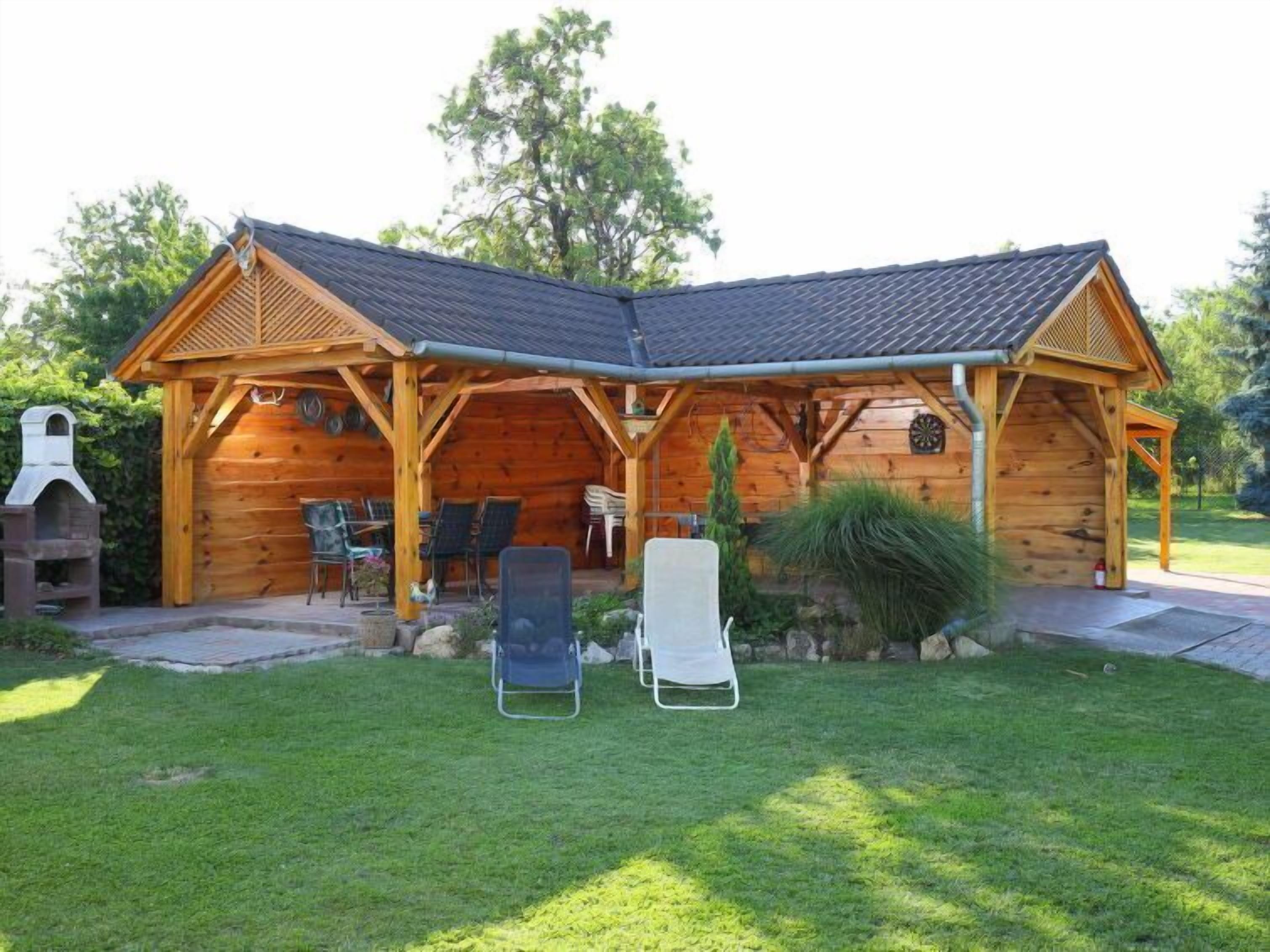 Een houten hut met een overdekt terras en een barbecue.