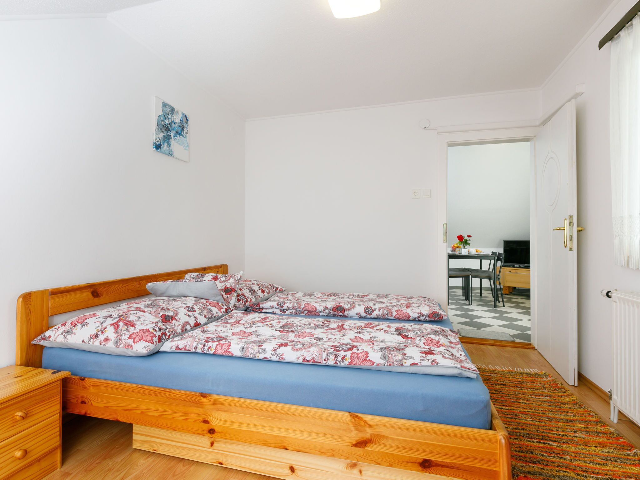 A bedroom with a wooden bed, a nightstand, and a small table with a chair.