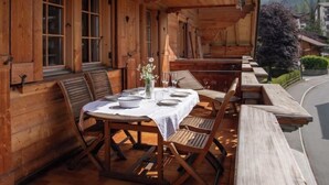 Zona pranzo esterna in legno con un tavolo imbandito per due persone, circondato da panche di legno.