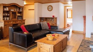 Un accogliente soggiorno con un divano in pelle nera, mobili in legno e una parete decorata con pietra.