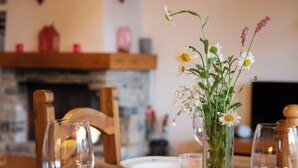 Un tavolo da pranzo con un vaso di fiori, bicchieri da vino e piatti.