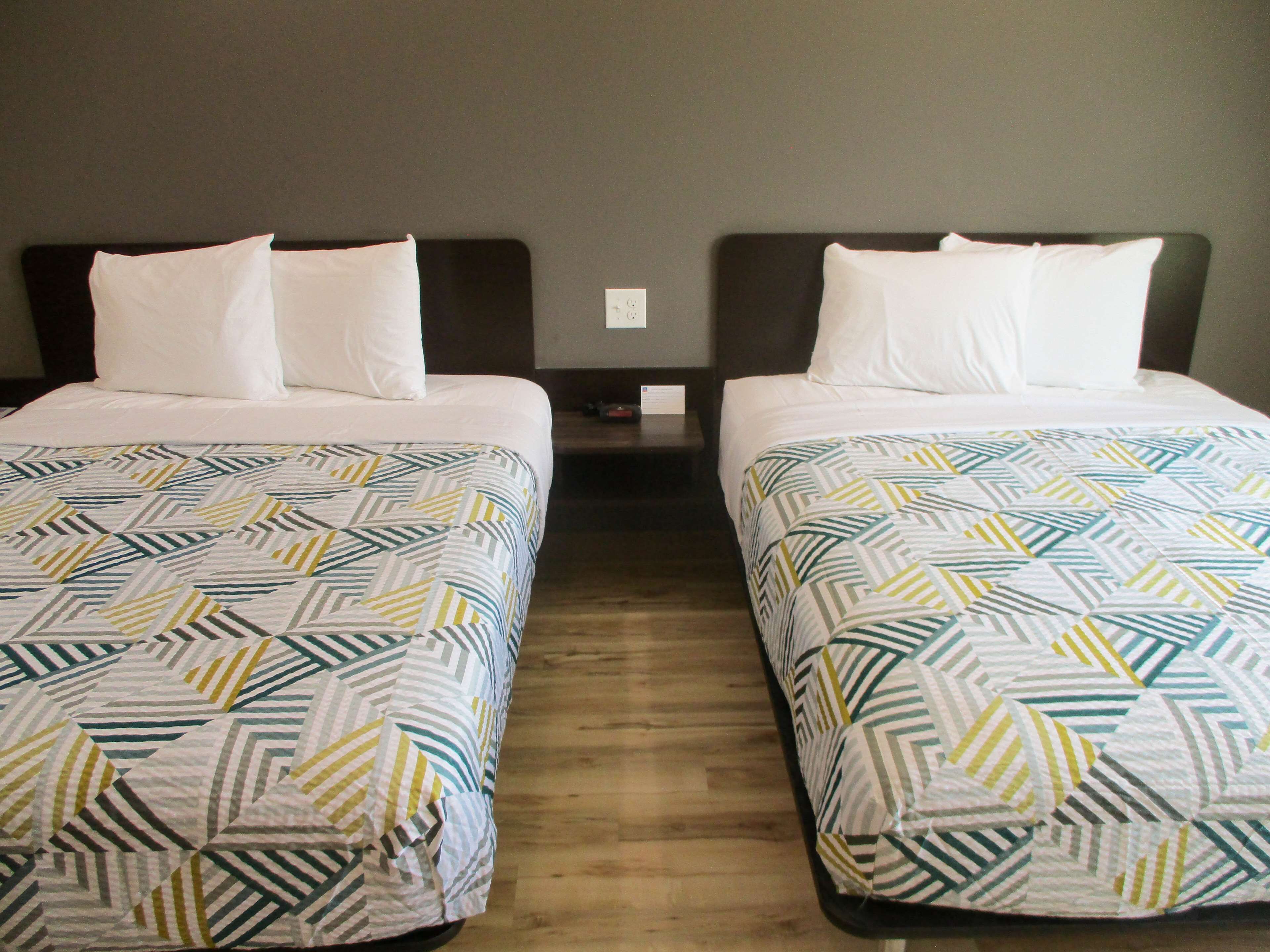 Two twin beds with patterned bedding, a wooden floor, and a dark headboard.