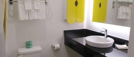 A bathroom with a toilet, a sink, and a mirror. There are towels on a rack above the toilet and a shelf above the sink.