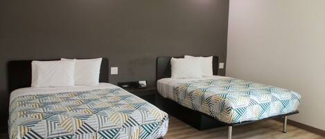 Two single beds with patterned bedding in a room with wooden flooring and dark walls.