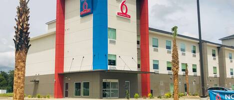 A hotel with a red and blue facade, multiple windows, and a parking lot.