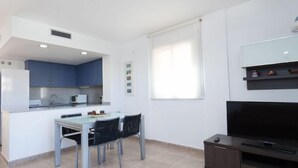 Un espacio habitable compacto con kitchenette, comedor y televisor de pantalla plana.