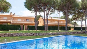 Una piscina con un muro de piedra y un edificio con techo de tejas al fondo.